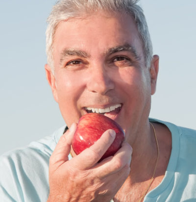 older man eating an apple after getting dentures