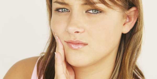 woman holding jaw in pain